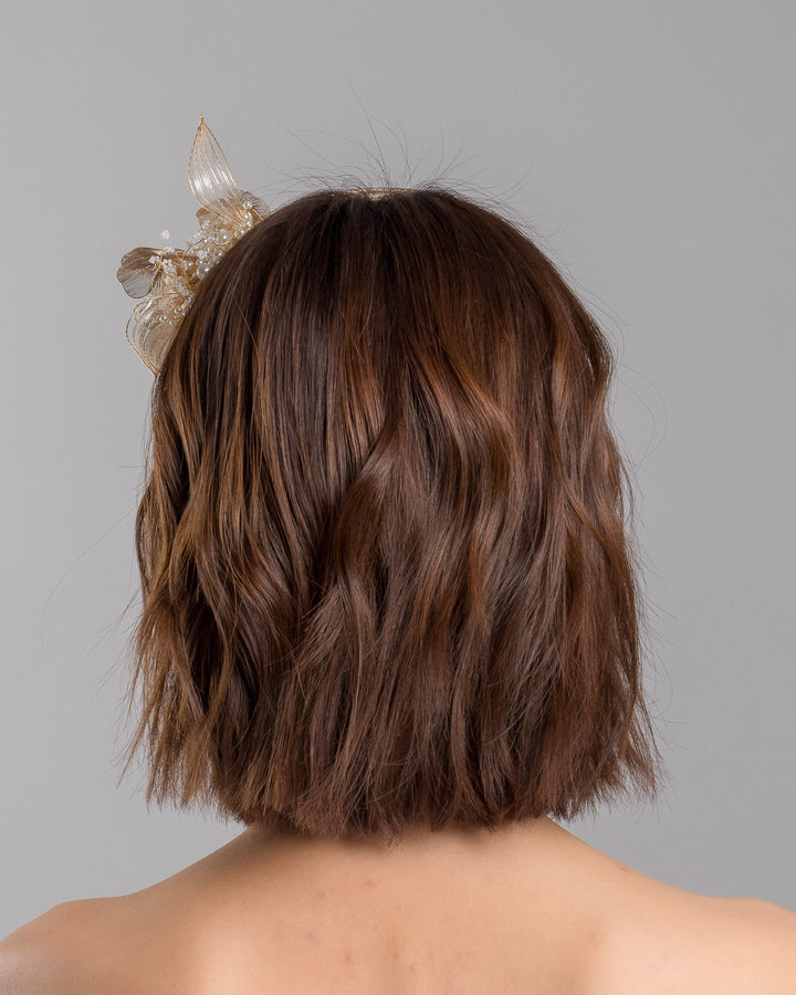 The model is showcasing the back side close up of the gold metallic headband with sculpted floral and leaf embellishments, featuring delicate ivory bead details and an elegant asymmetrical design. Designed and made by Merve Bayindir Millinery.
