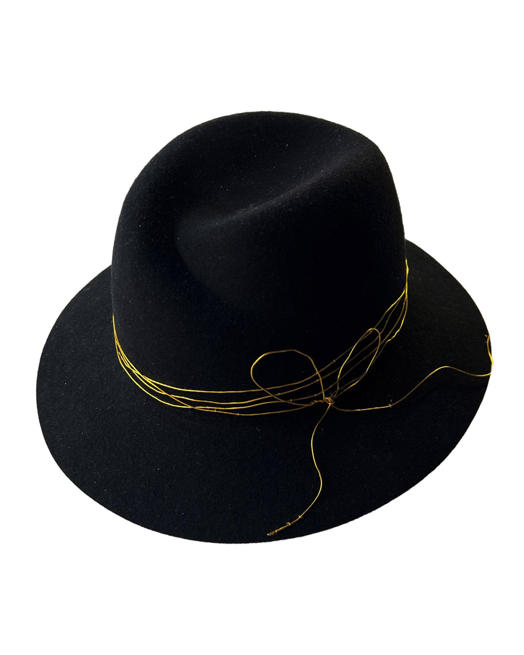Still life picture of the Ahether Fedora hat, a classic silhouette, crafted in black felt and adorned with freeform golden wirework, finished with an abstract metallic bow motif. Designed by Merve Bayindir.