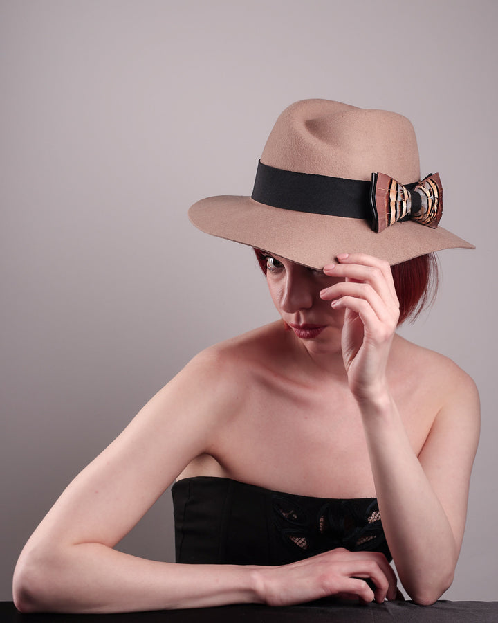 The model is showcasing the right front  above angle of the Amelie, a classic fedora hat featuring a feathered bow detail; it&