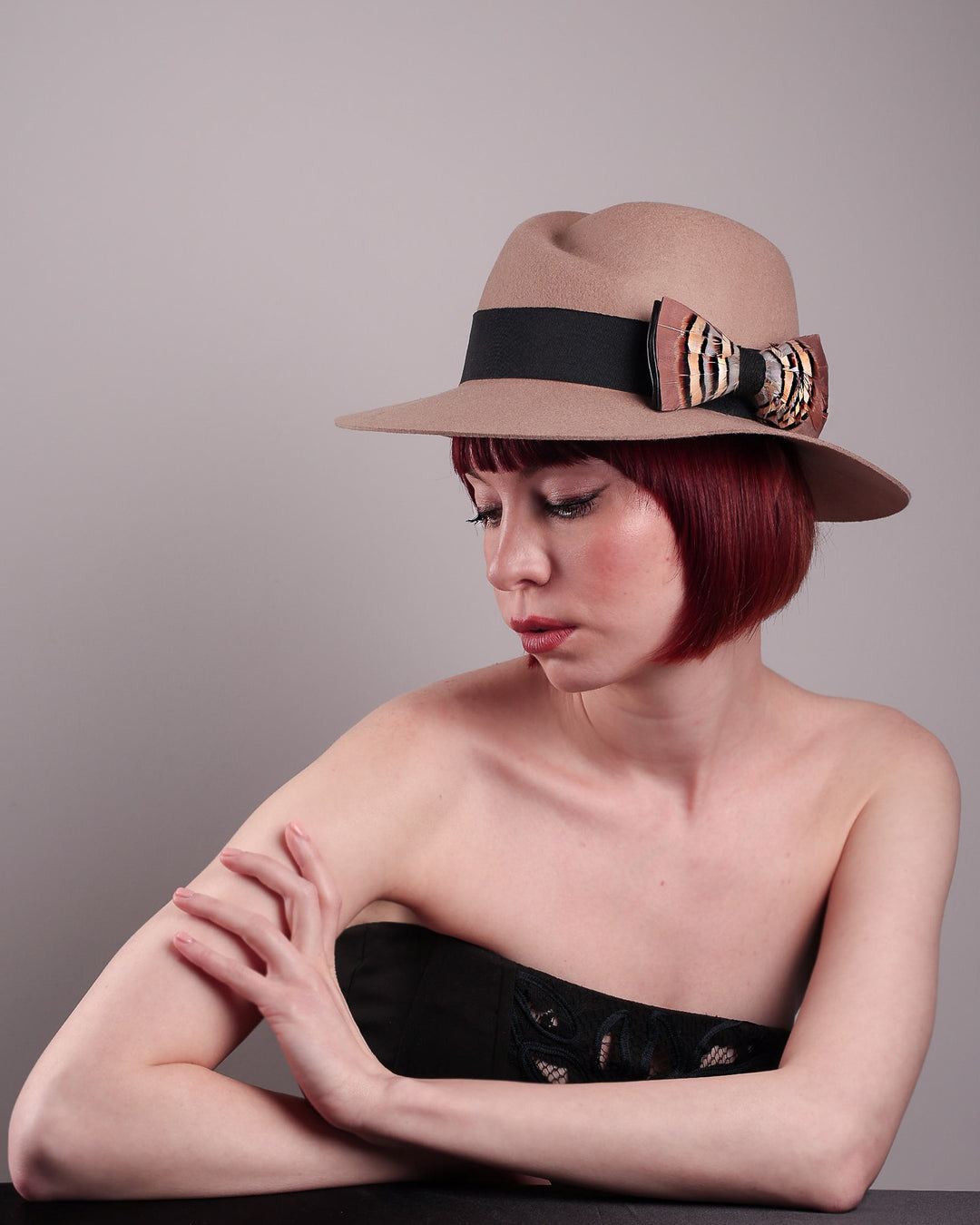 The model is showcasing the right front straight  of the Amelie, a classic fedora hat featuring a feathered bow detail; it&