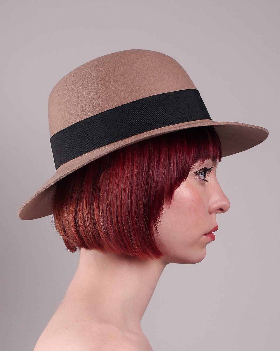 The model is showcasing the right side close up of the Amelie, a classic fedora hat featuring a feathered bow detail; it&
