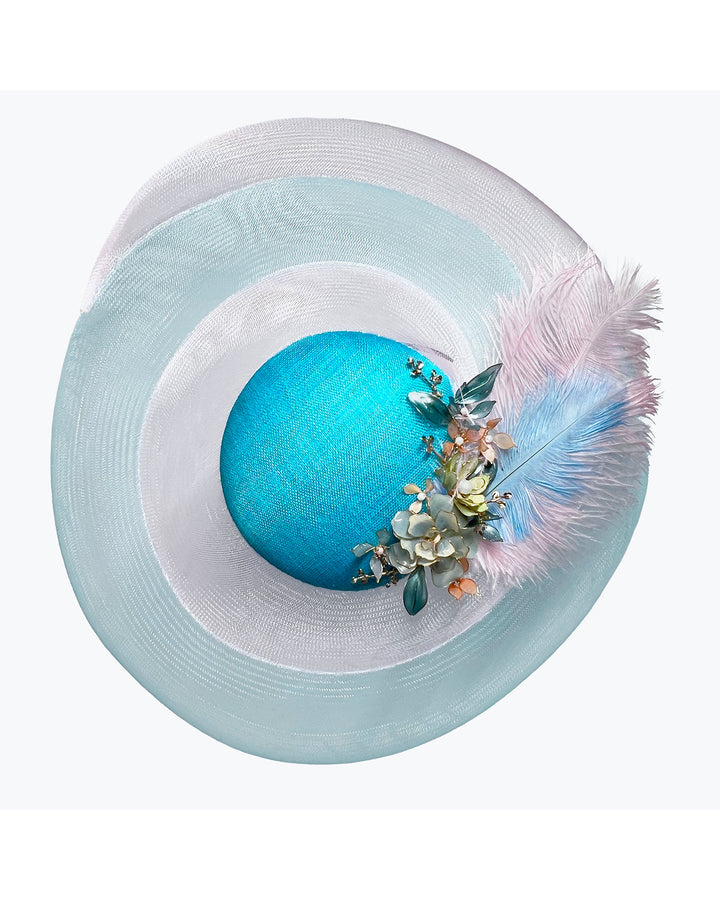 Turquoise sinamay center base fascinator framed by concentric white and pale aqua sinamay rings, adorned with soft pastel feathers and delicate floral embellishments for a light, ethereal finish. Designed and made by Merve Bayindir Millinery