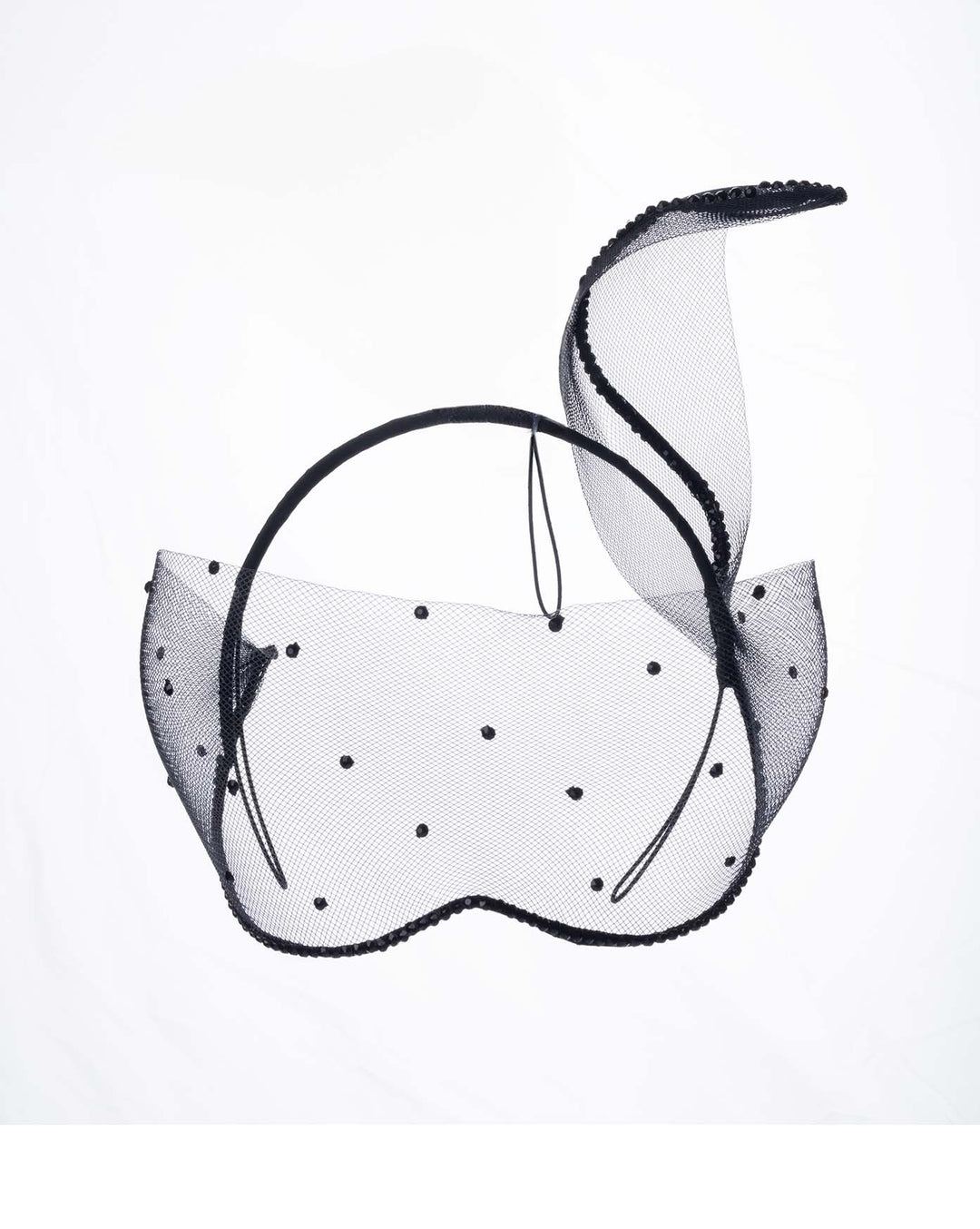 The black mesh headpiece is adorned with small black crystals. It features a design with a prominent bow-like structure on one side embellished with black crystals. The delicate mesh has a wire band to be fitted to the head. Made by Merve Bayindir Millinery.