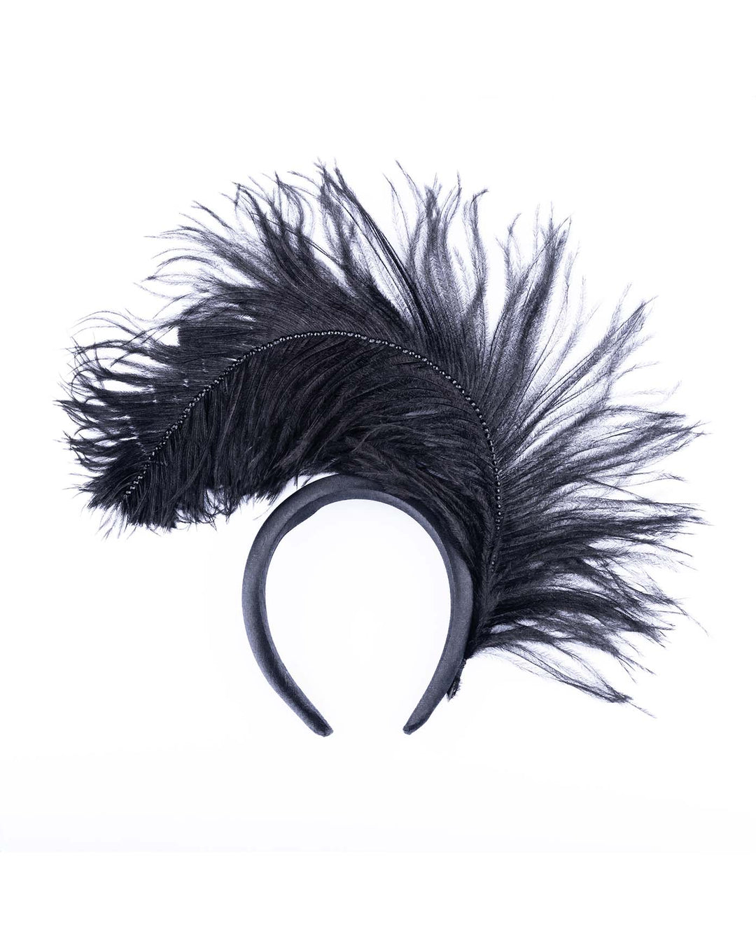 A luxury black sateen headband fitted with a large black ostrich feather on one side curving on top of the headband. The ostrich feather is adorned with black crystals in the centre. The ostrich feather on the headband creates an illusion of standing in the air. This piece is perfect for high-fashion events as well as costume parties.