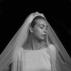 The picture showcases a bride with a bow decorated veil