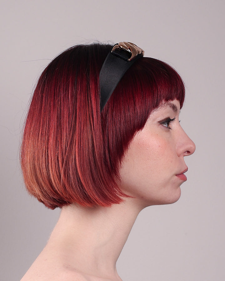The model showcases the right side close up of the Celeste Headband, handcrafted from a satin black Alice headband and crowned with a statement gold chain. Designed by Merve Bayindir.