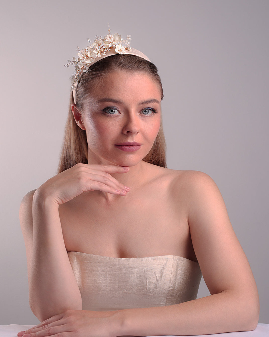 The model is showcasing the front of an Alice style flat silk headband decorated with ivory resin flower arrangment with beads.