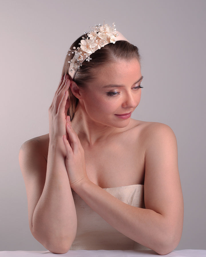 The model is showcasing the top right side of an Alice style flat silk headband decorated with ivory resin flower arrangment with beads.