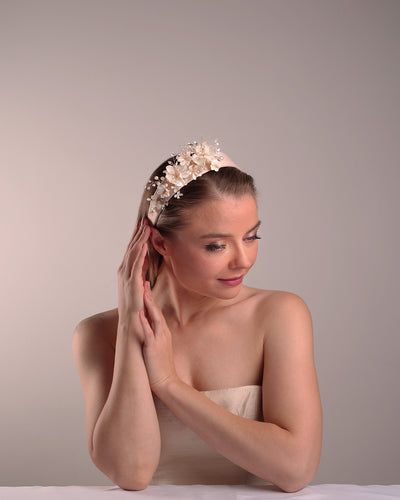 The model is showcasing the top right side of an Alice style flat silk headband decorated with ivory resin flower arrangment with beads.