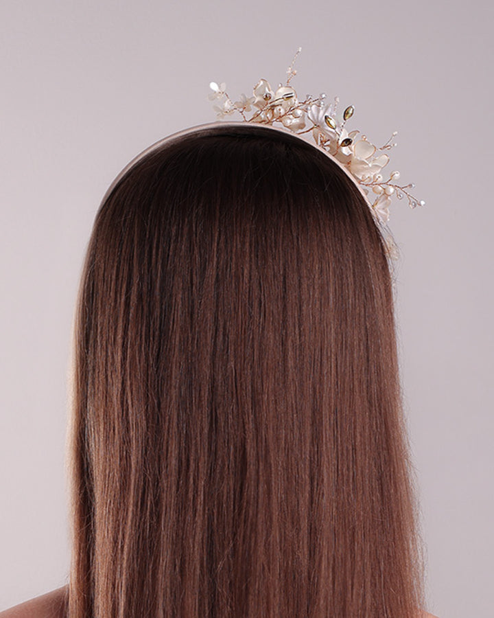 The model is showcasing the back of an Alice style flat silk headband decorated with ivory resin flower arrangment with beads.
