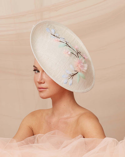 Medium size white saucer style fascinator hat adorned with a feather and sequence motif.