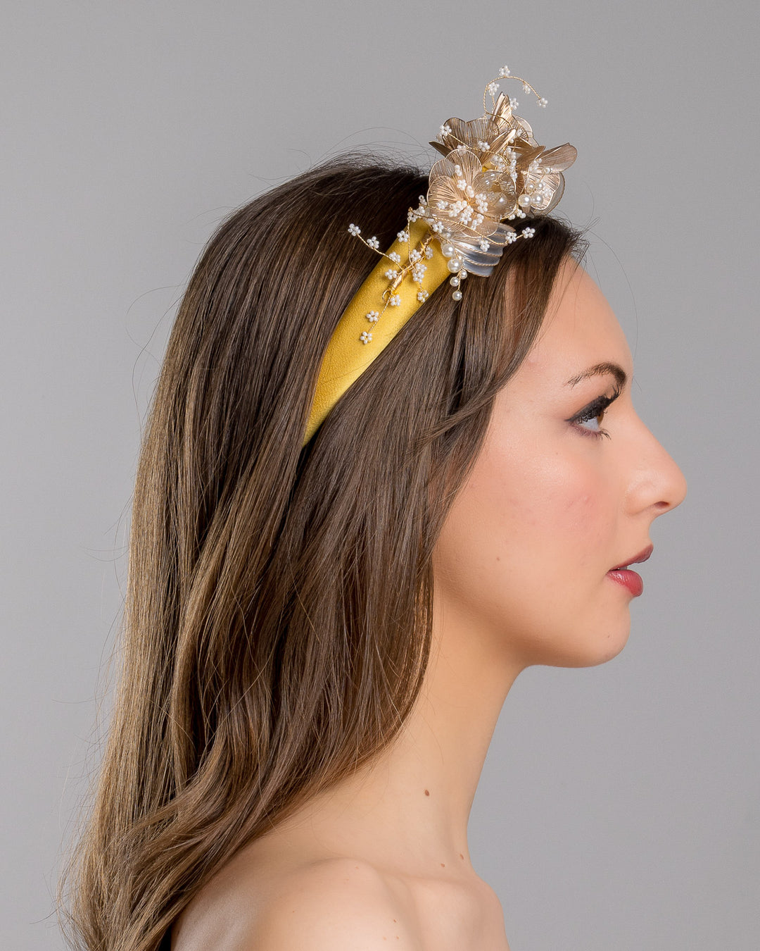 Model is showcasing the right side of the yellow satin headband decorated with bead flowers , resin flowers and leaves with golden wires. Made by Merve Bayindir.