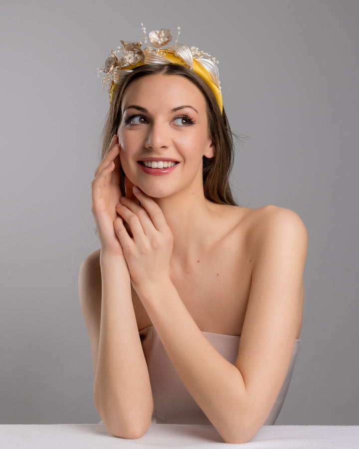 Model is posing wearing mustard yellow satin headband decorated with bead flowers , resin flowers and leaves with golden wires. Made by Merve Bayindir.