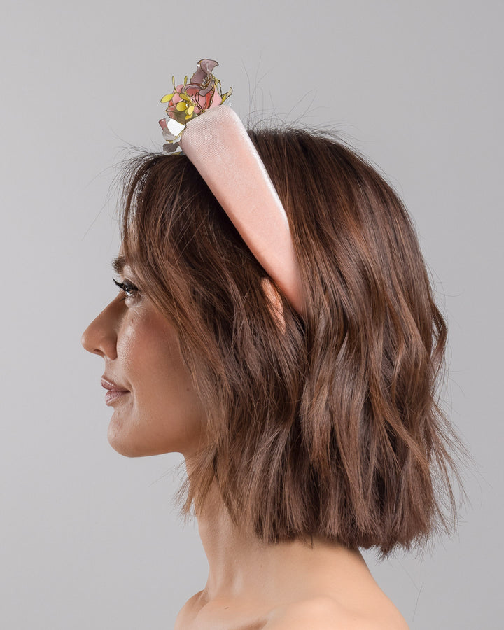 Model is showcasing the left side of pink velvet thick headband, decorated with multi coloured resin flower bouquet design. Made by Merve Bayindir millinery.