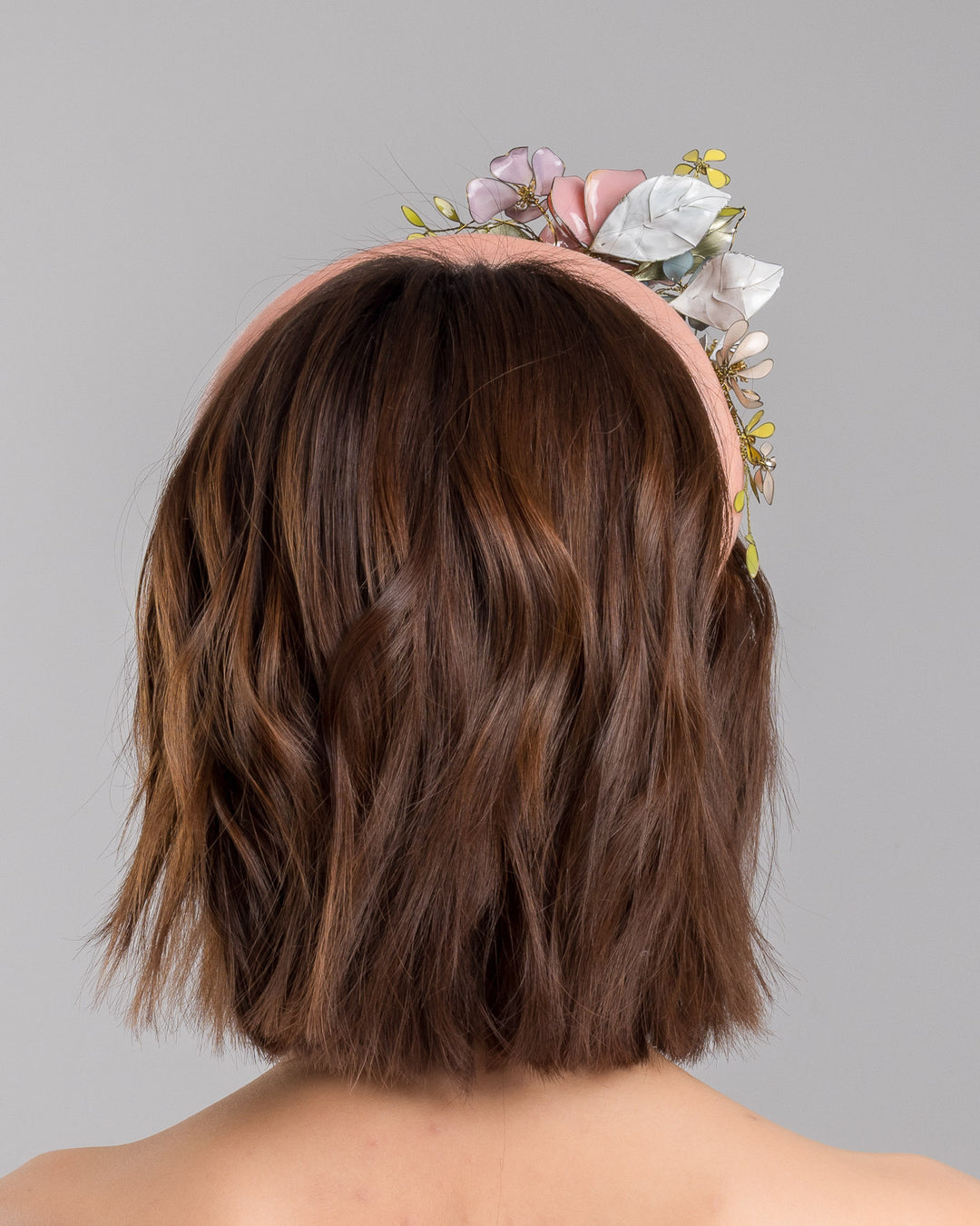 Model is showcasing the back of pink velvet thick headband, decorated with multi coloured resin flower bouquet design. Made by Merve Bayindir millinery.