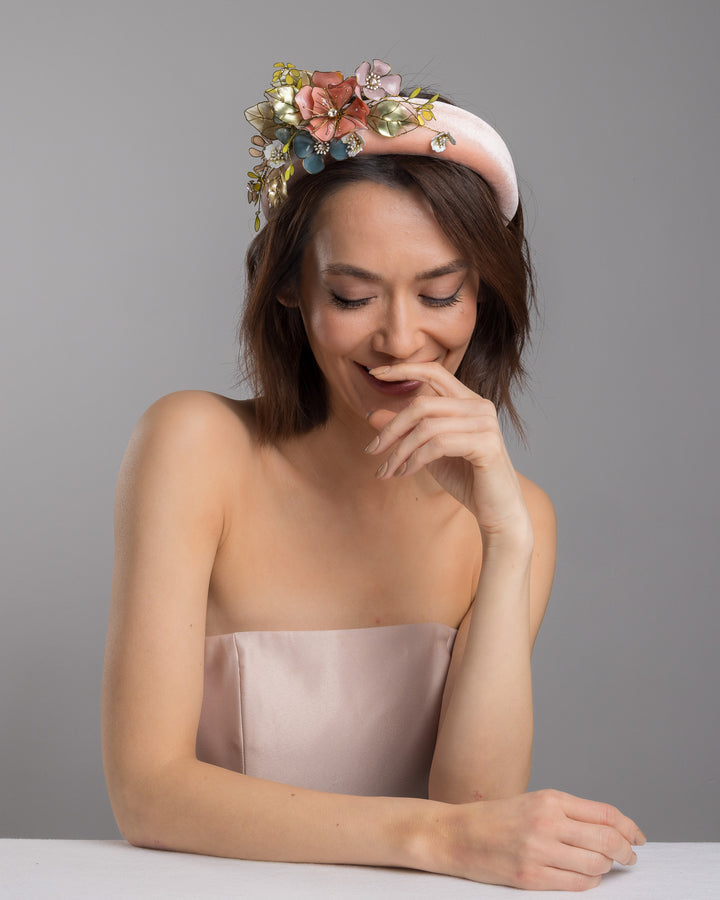 Model is posing wearing Demitto pink velvet thick headband, decorated with multi coloured resin flower bouquet design. Made by Merve Bayindir millinery.