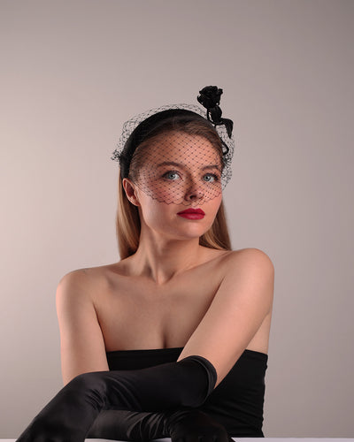 Model is showcasing the front right side of semi high black silk heaband with a black veil adroned with a handmade black sateen rose on the right side.