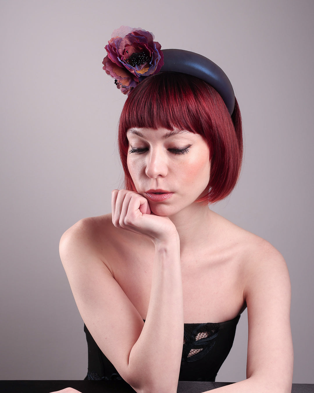 Model wearing and showcasing the right front side of an iridescent Eclipse Headband with layered flower detail in deep purple, bronze, and wine tones, handcrafted by Merve Bayindir.
