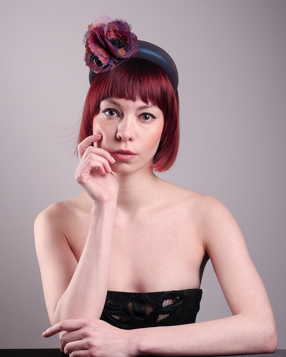 Model wearing and showcasing the front side of an iridescent Eclipse Headband with layered flower detail in deep purple, bronze, and wine tones, handcrafted by Merve Bayindir.