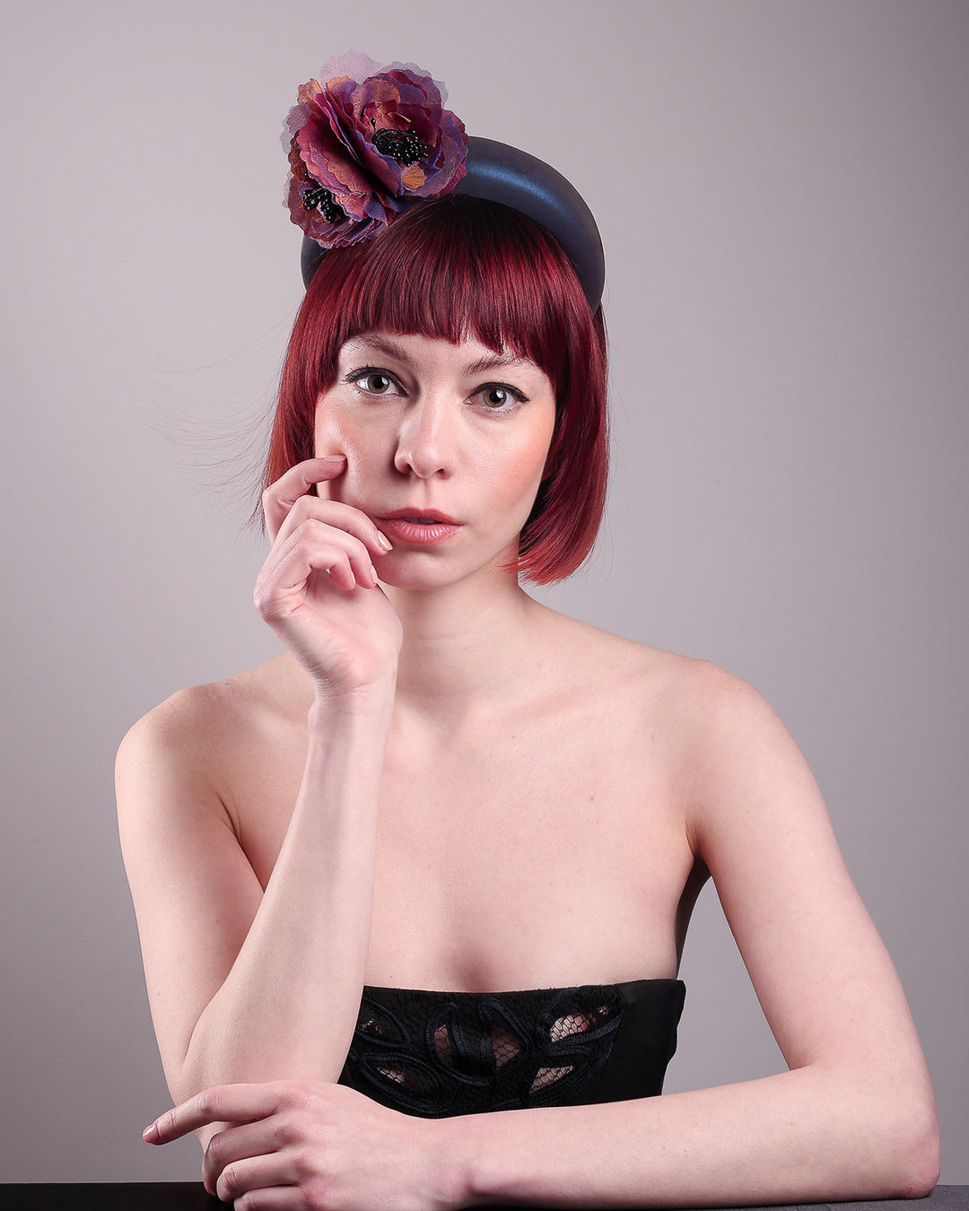 Model wearing and showcasing the front side of an iridescent Eclipse Headband with layered flower detail in deep purple, bronze, and wine tones, handcrafted by Merve Bayindir.