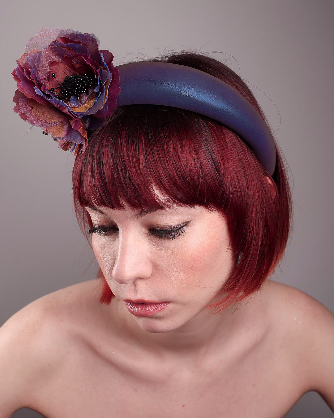 Model wearing and showcasing the top close up of an iridescent Eclipse Headband with layered flower detail in deep purple, bronze, and wine tones, handcrafted by Merve Bayindir.