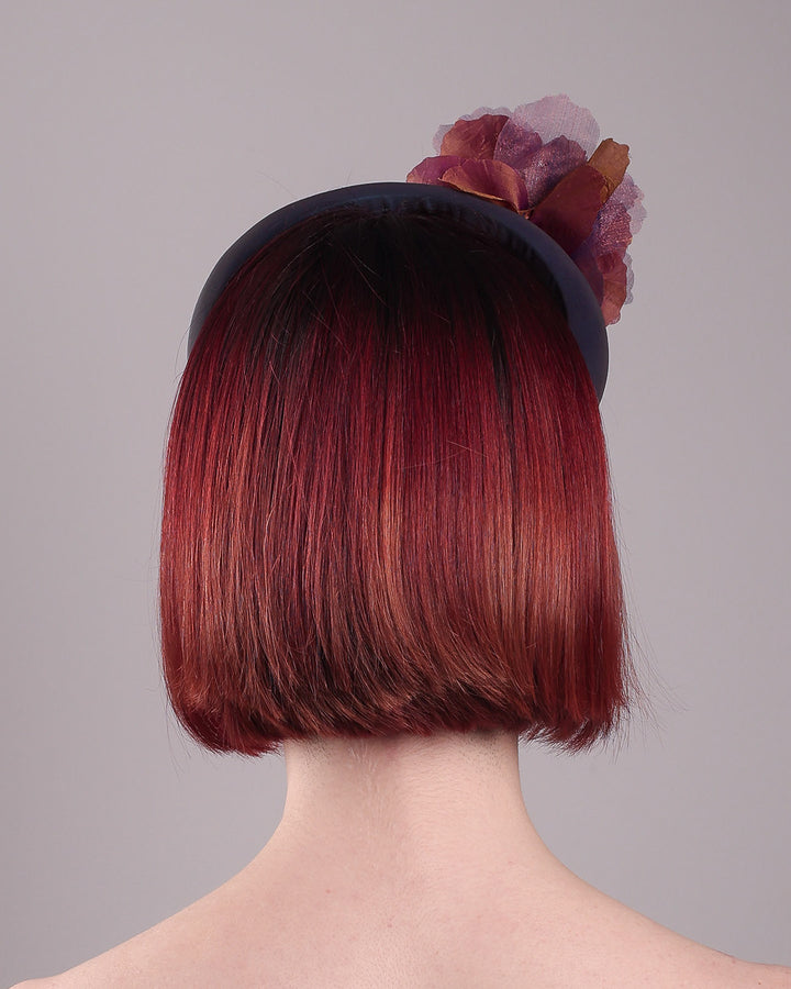Model wearing and showcasing the back close up of an iridescent Eclipse Headband with layered flower detail in deep purple, bronze, and wine tones, handcrafted by Merve Bayindir.