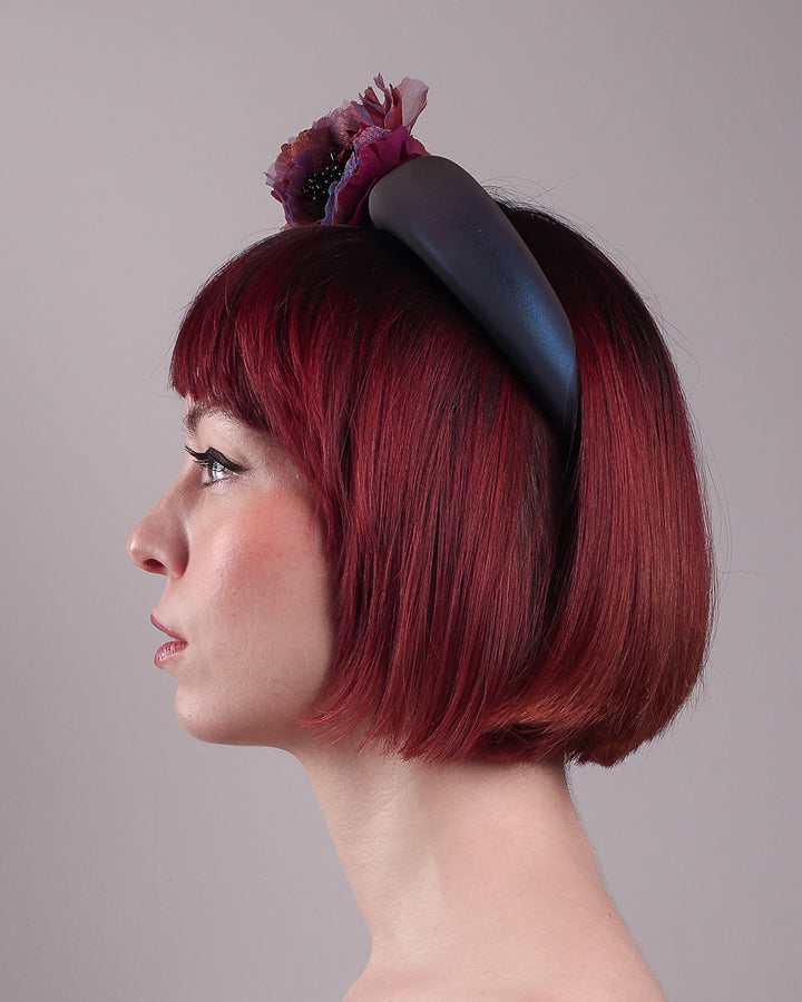Model wearing and showcasing the right side close up of an iridescent Eclipse Headband with layered flower detail in deep purple, bronze, and wine tones, handcrafted by Merve Bayindir.