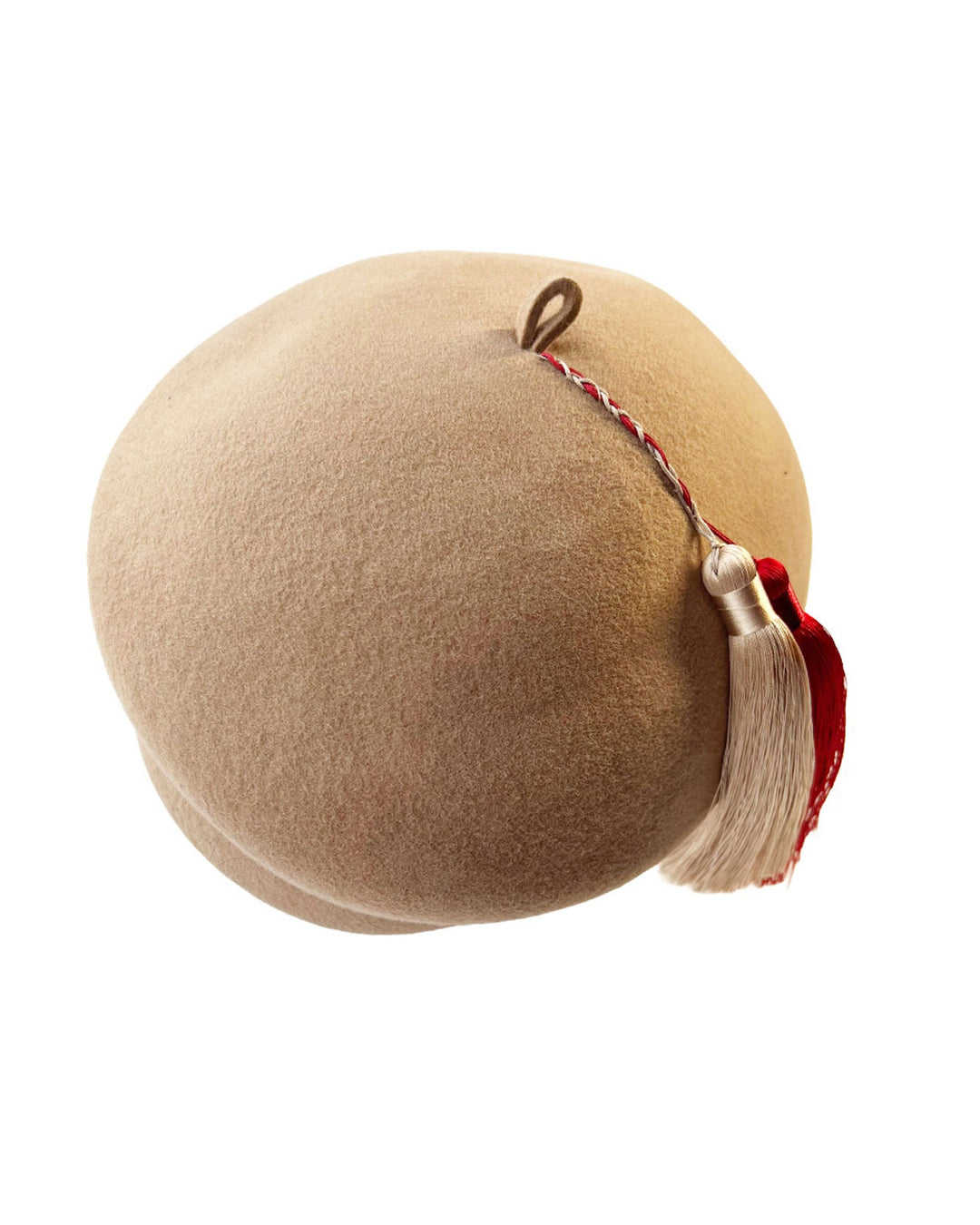 Still life picture of Elera Felt Beret Hat, made of smooth camel wool felt. This structured beret features a dramatic two-tone tassel in crimson and cream, gently draped to one side from a polished metallic accent. Designed by Merve Bayindir. 