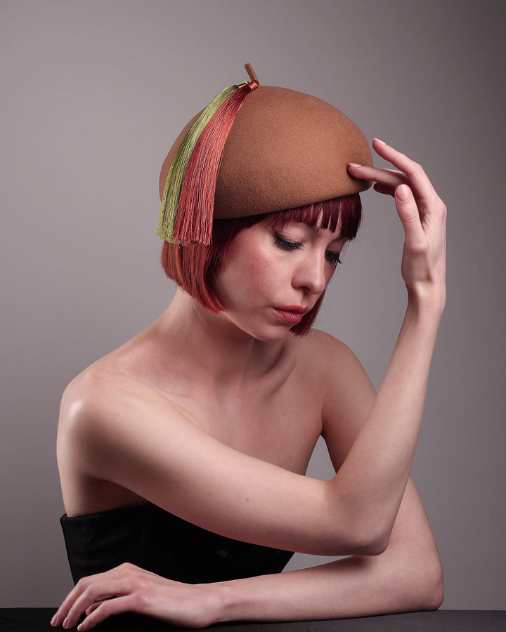 The model is showcasing the front right angle of the Faye Beret Hat, handcrafted in camel wool felt. It&