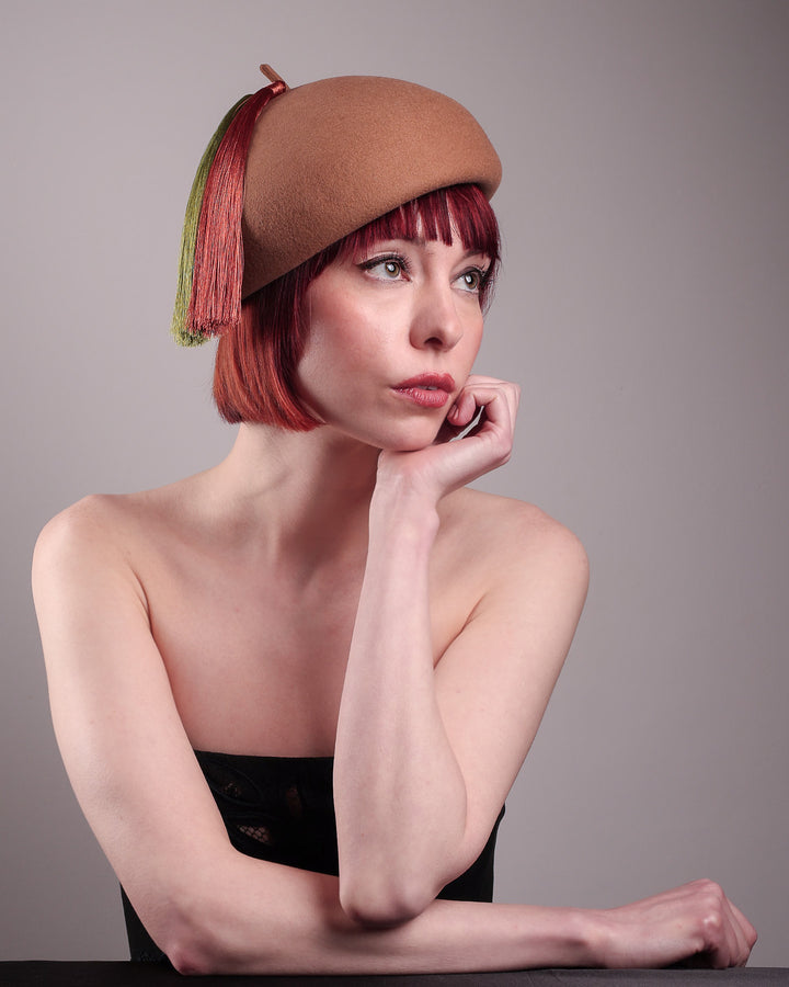 The model is showcasing the front right side from the below angle of the Faye Beret Hat, handcrafted in camel wool felt. It&