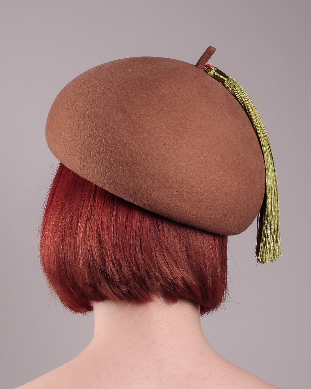 The model is showcasing the back of the Faye Beret Hat, handcrafted in camel wool felt. It&
