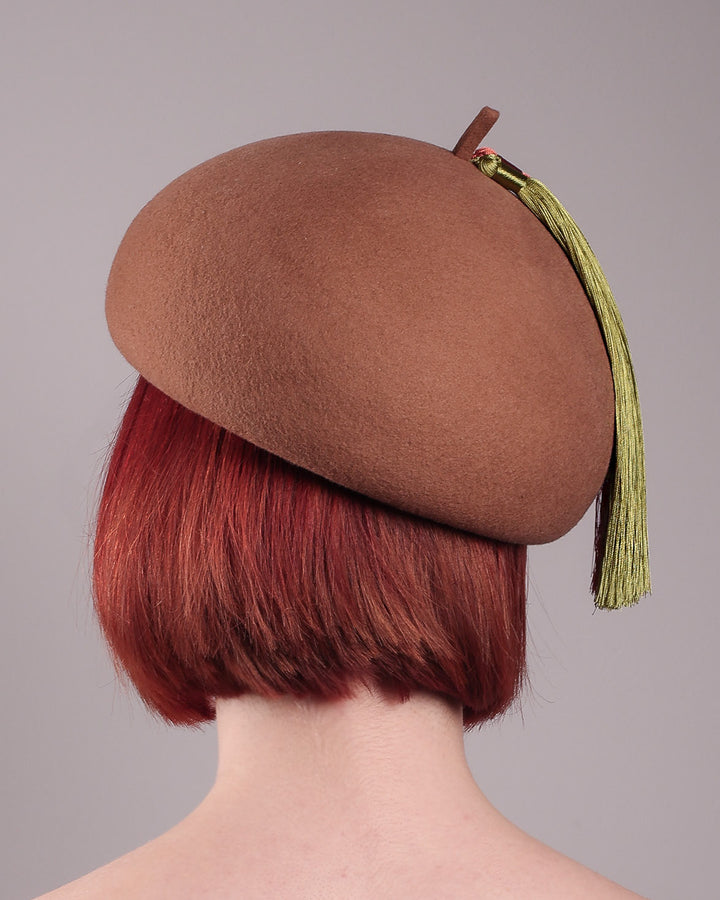 The model is showcasing the back of the Faye Beret Hat, handcrafted in camel wool felt. It&