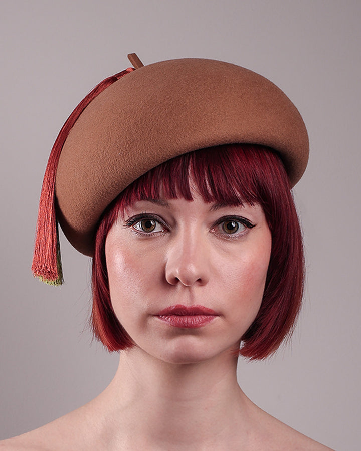 The model is showcasing the front close up of the Faye Beret Hat, handcrafted in camel wool felt. It&