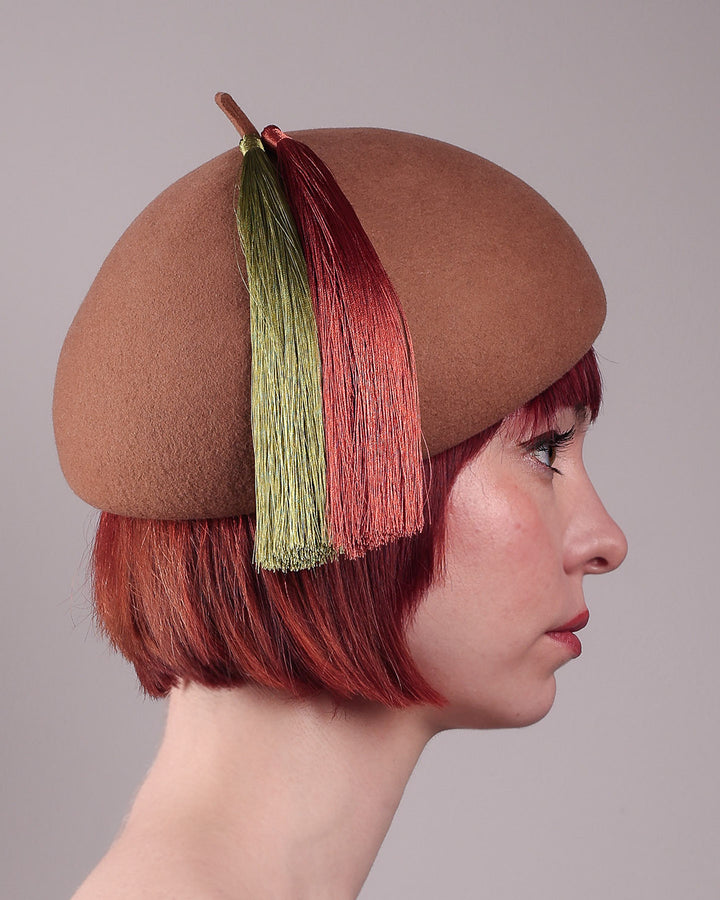 The model is showcasing the right side close up of the Faye Beret Hat, handcrafted in camel wool felt. It&