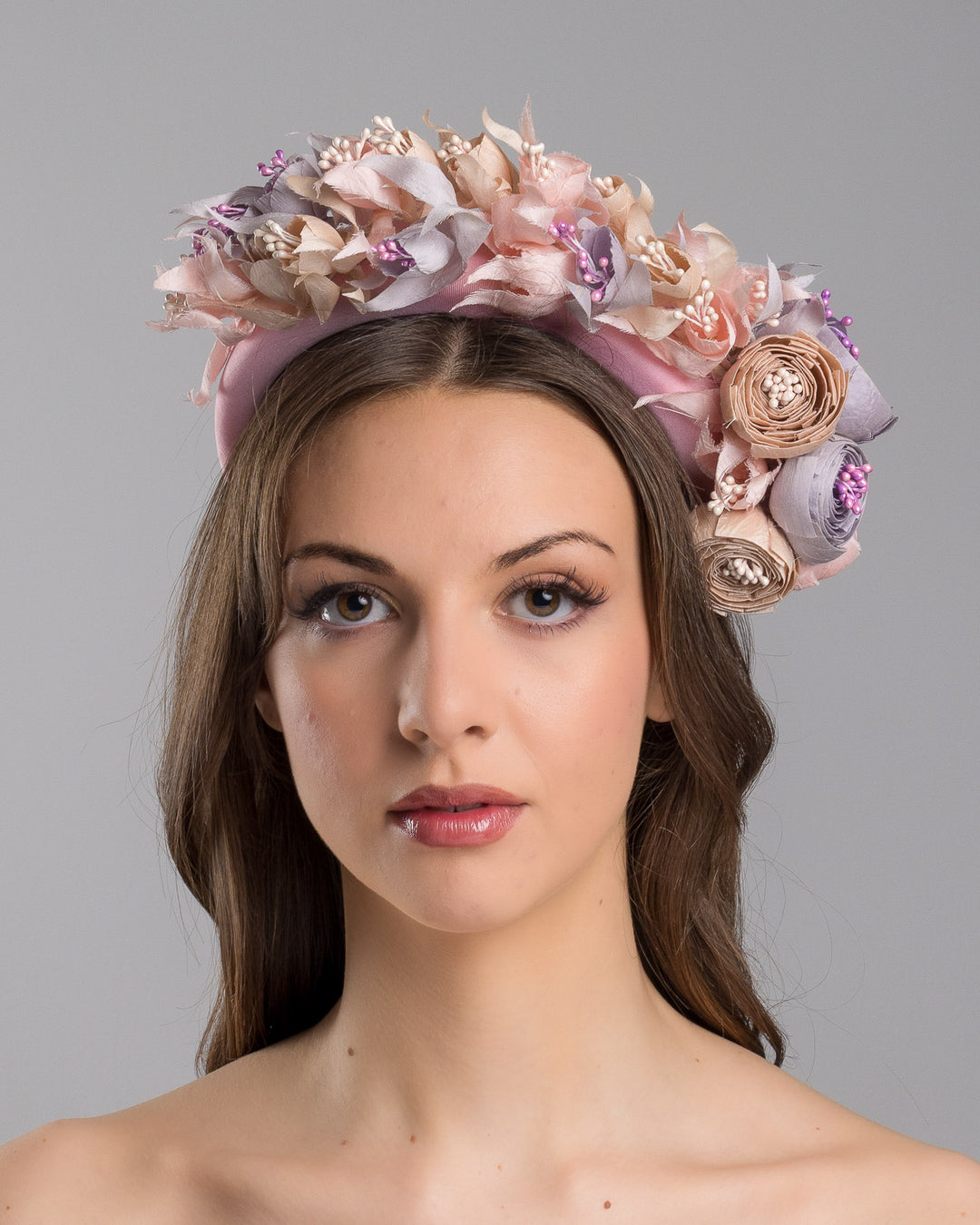 Model showcasing the front side close up of high pink headband decorated with custom made silk taffeta lilac, pink and ecru bouquet of peony and fuchsia flowers. Made by Merve Bayindir.