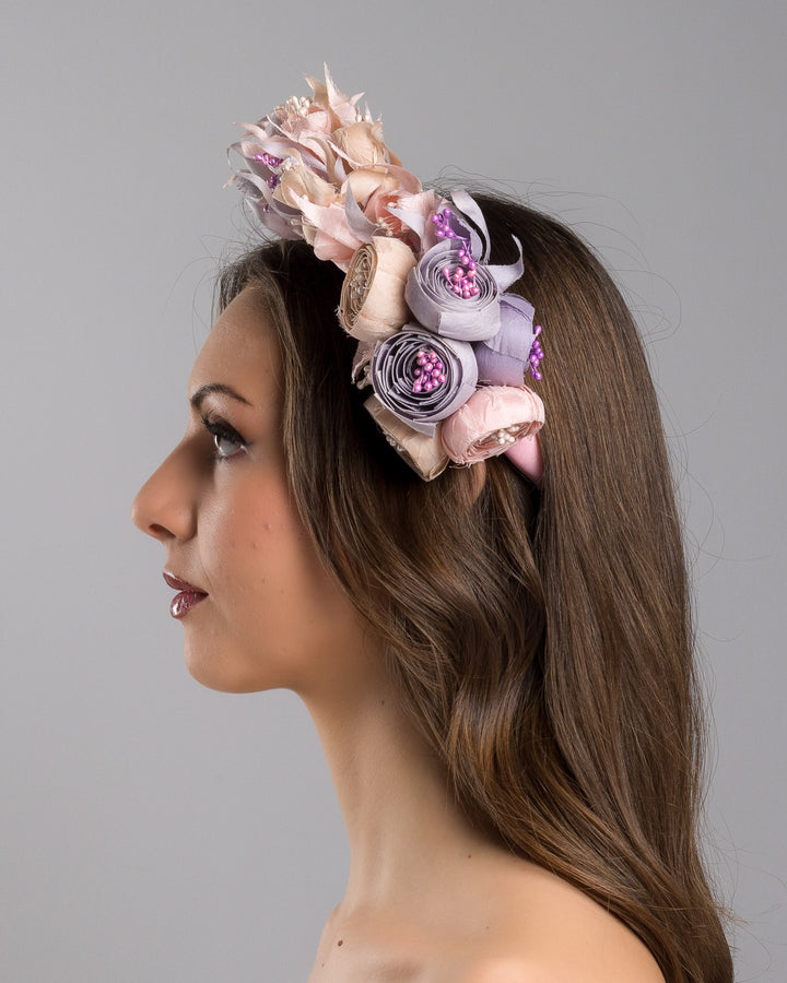 Model showcasing the left side close up of high pink headband decorated with custom made silk taffeta lilac, pink and ecru bouquet of peony and fuchsia flowers. Made by Merve Bayindir.