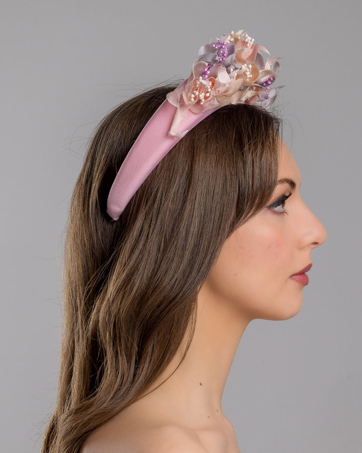 Model showcasing the right side close up of high pink headband decorated with custom made silk taffeta lilac, pink and ecru bouquet of peony and fuchsia flowers. Made by Merve Bayindir.