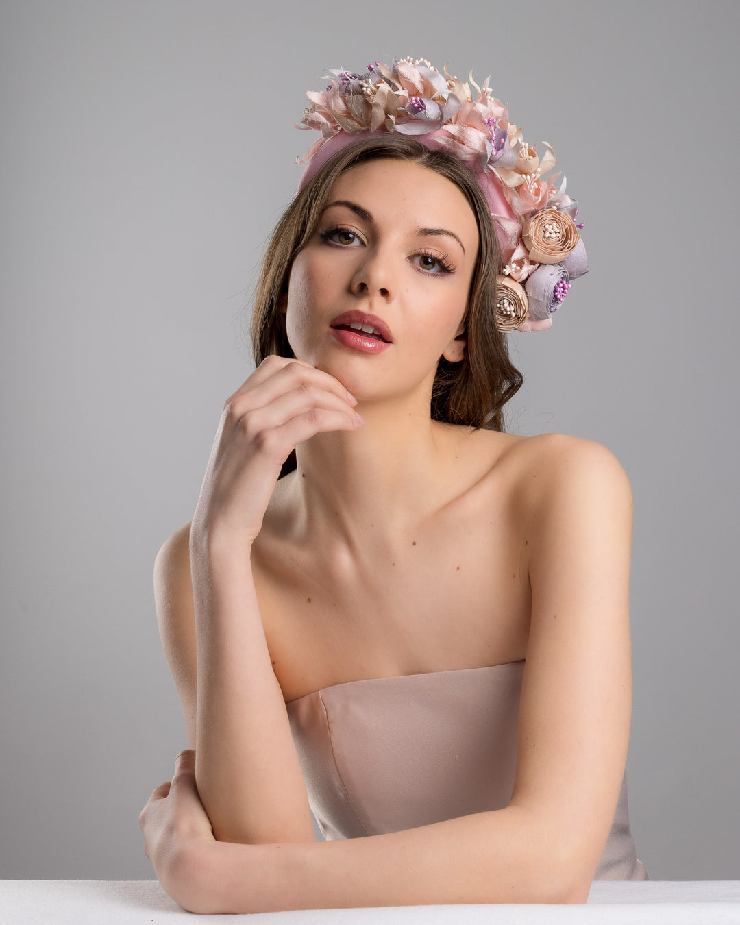 Model is posing wearing Flamenco a high pink headband decorated with custom made silk taffeta lilac, pink and ecru bouquet of peony and fuchsia flowers. Made by Merve Bayindir.