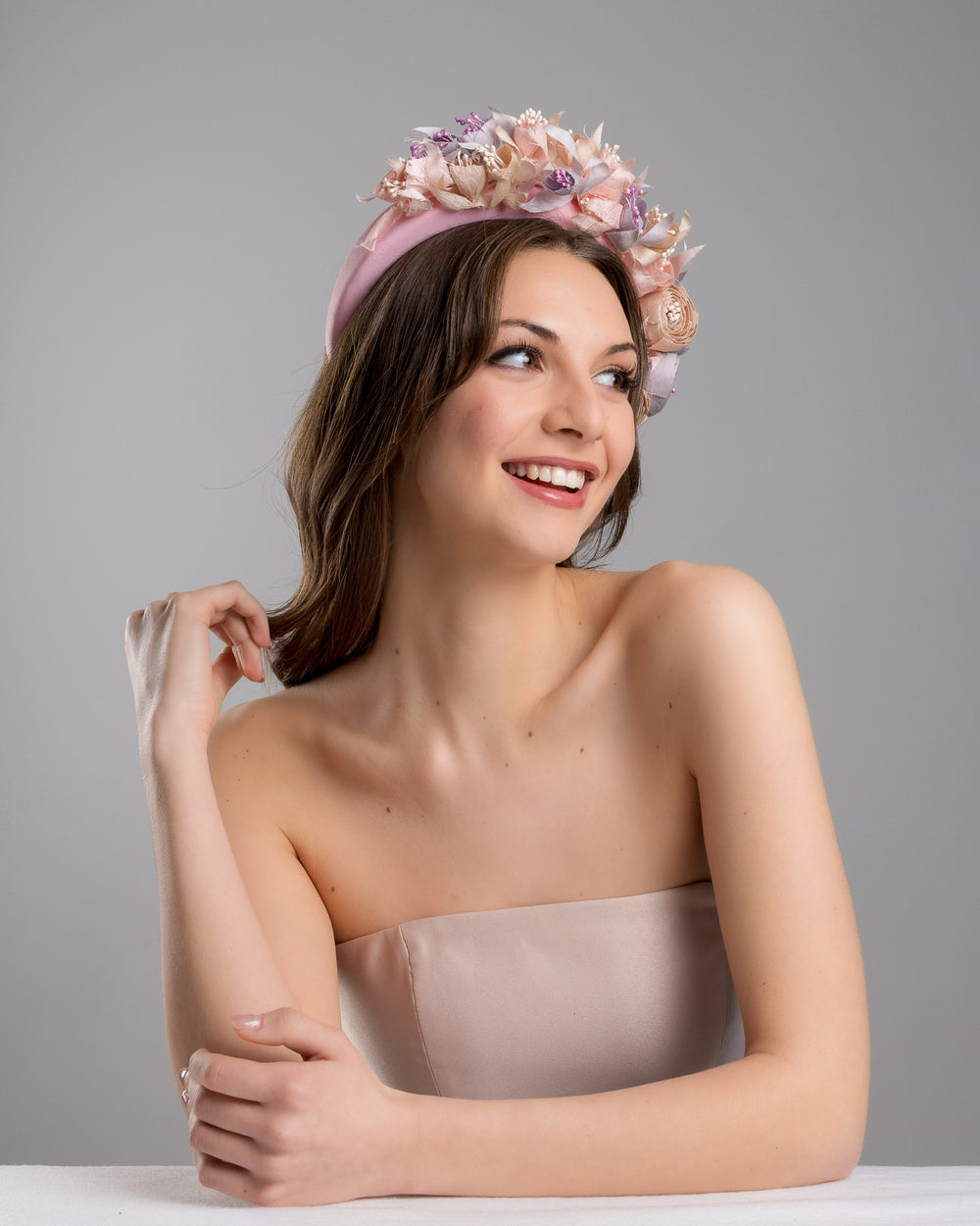 Model is posing wearing Flamenco a high pink headband decorated with custom made silk taffeta lilac, pink and ecru bouquet of peony and fuchsia flowers. Made by Merve Bayindir.