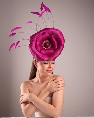 Model is showcasing the front view of large fascinator adorned with a fuchsia hand-made silk-abaca large flower, placed on a lilac coloured mini saucer. The mini saucer base is fixed on a custom headband and secured with an additional elastic.