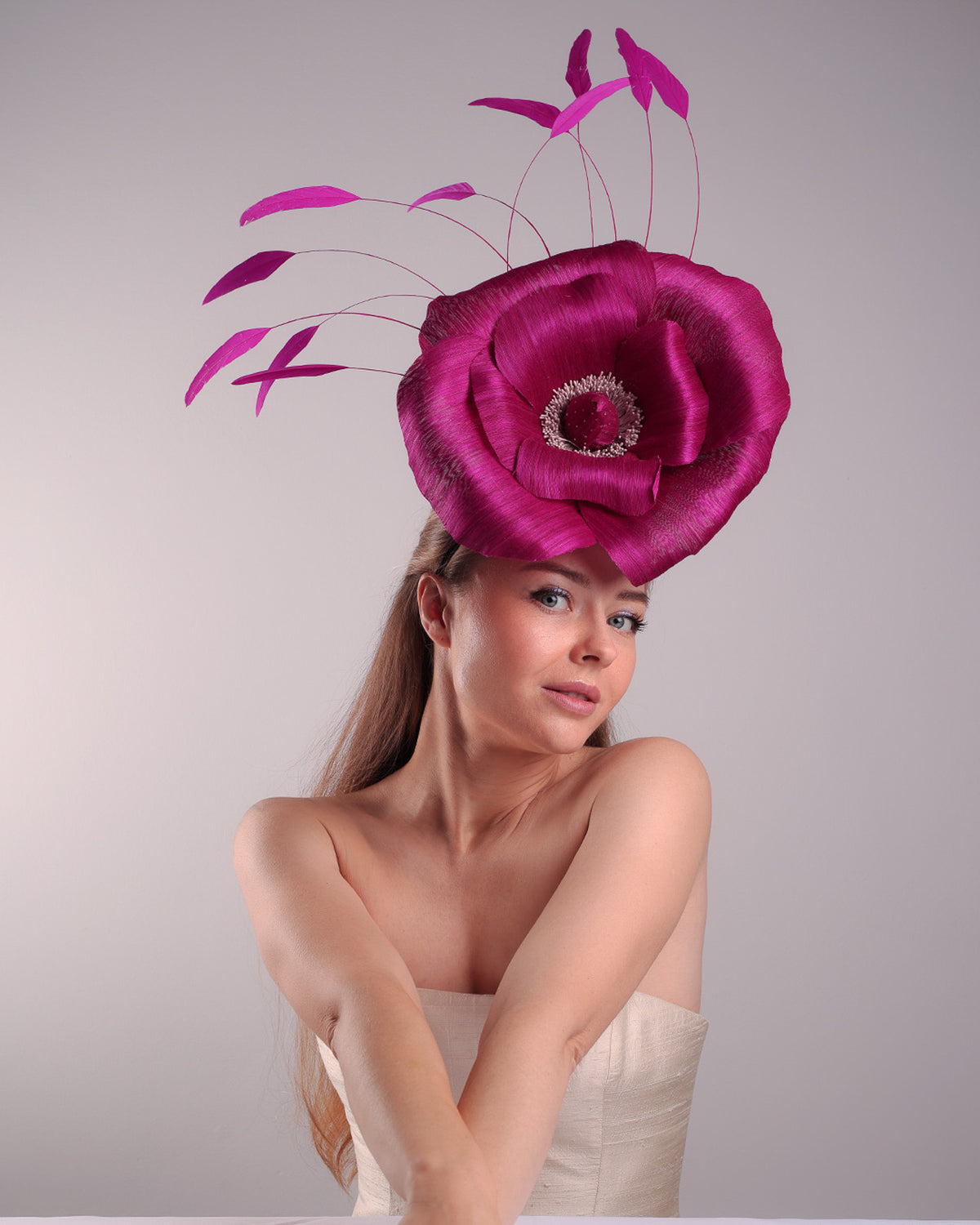 Model is showcasing the right angled front view of large fascinator adorned with a fuchsia hand-made silk-abaca large flower, placed on a lilac coloured mini saucer. The mini saucer base is fixed on a custom headband and secured with an additional elastic.
