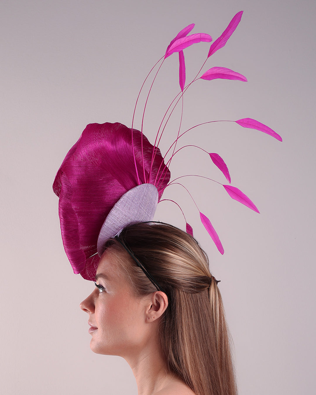 Model is showcasing left side of a large fascinator adorned with a fuchsia hand-made silk-abaca large flower, placed on a lilac coloured mini saucer. The mini saucer base is fixed on a custom headband and secured with an additional elastic.