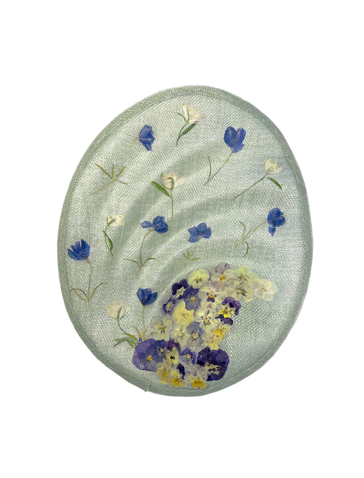 Round embroidered patch with floral design on a light green background
