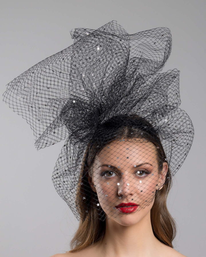 Model is showcasing the front of the Hera Fascinator made with custom three leg headband covered with double-threaded veil, embroidered with silver stars by Merve Bayindir millinery.