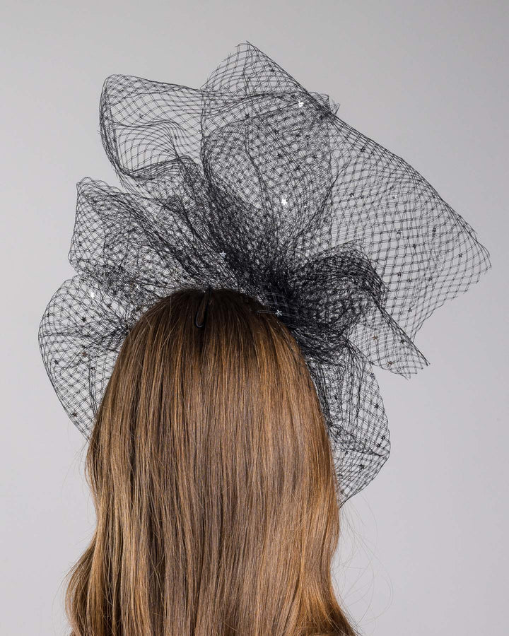 Model is showcasing the back of the Hera Fascinator made with custom three leg headband covered with double-threaded veil, embroidered with silver stars by Merve Bayindir millinery.