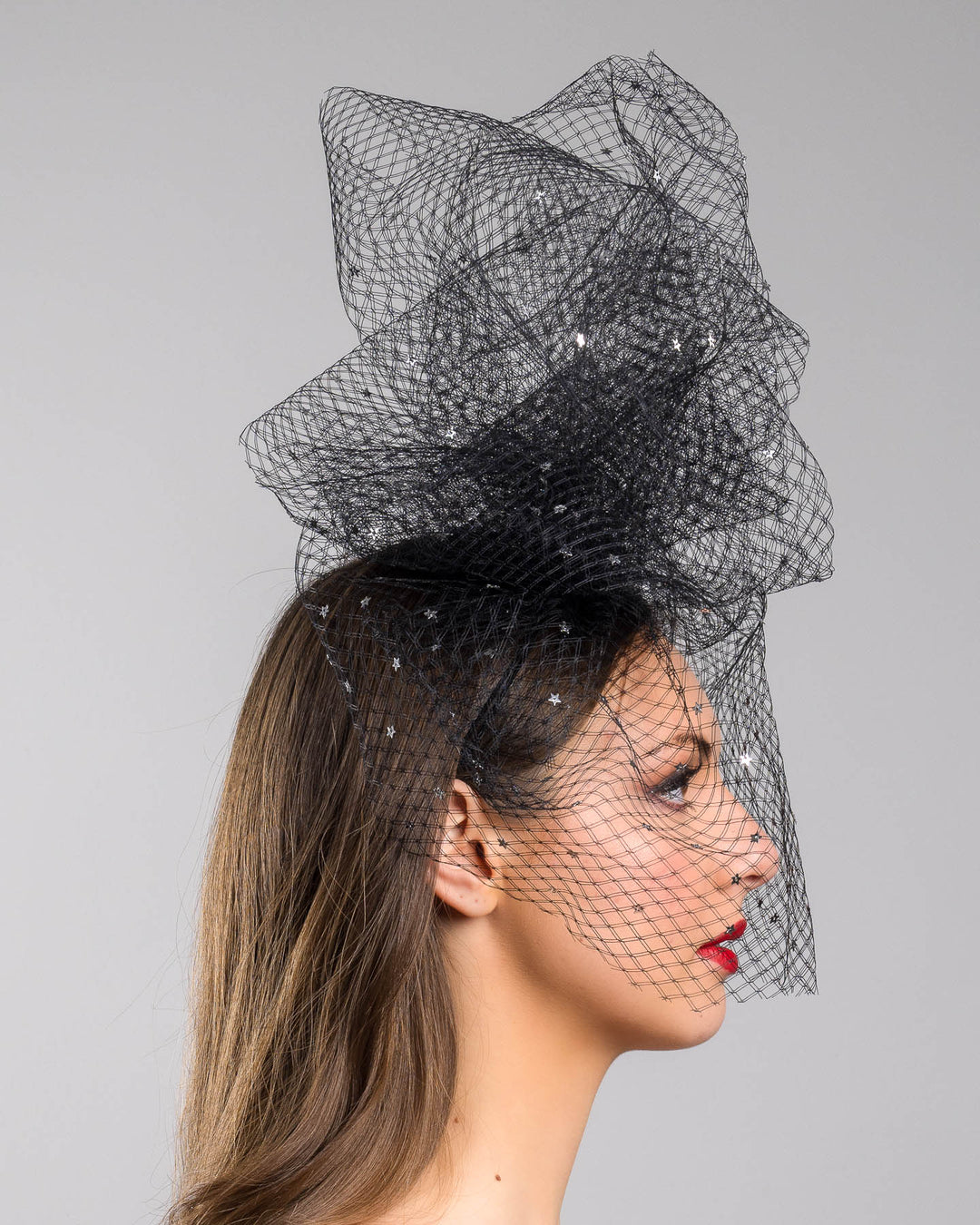 Model is showcasing the right side of the Hera Fascinator made with custom three leg headband covered with double-threaded veil, embroidered with silver stars by Merve Bayindir millinery.