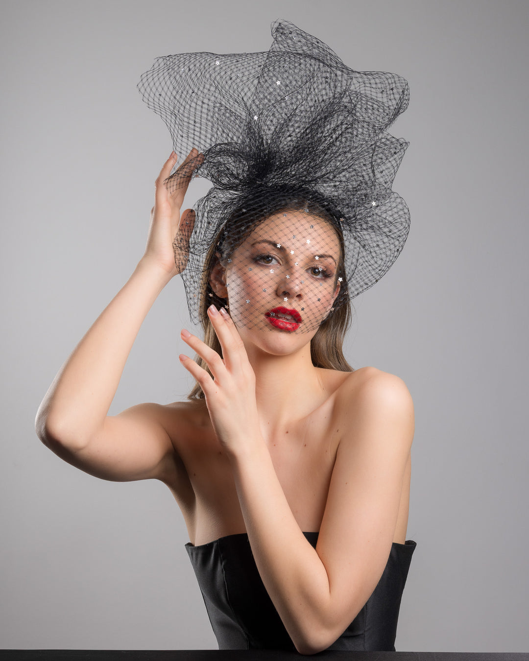 Model is posing wearing the Hera Fascinator made with custom three leg headband covered with double-threaded veil, extending like a cloud, embroidered with silver stars by Merve Bayindir millinery.