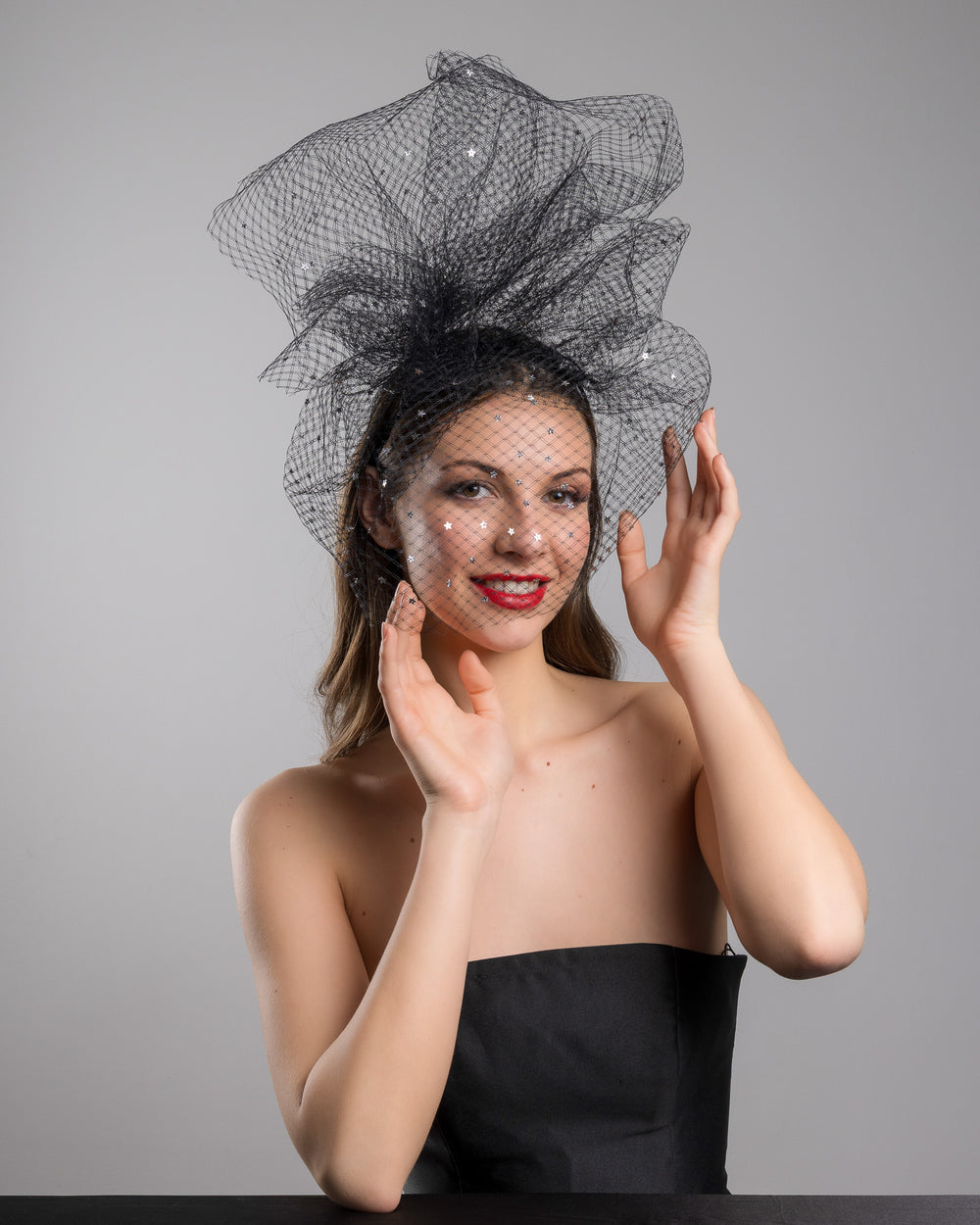 Model is posing wearing the Hera Fascinator made with custom three leg headband covered with double-threaded veil, extending like a cloud, embroidered with silver stars by Merve Bayindir millinery.