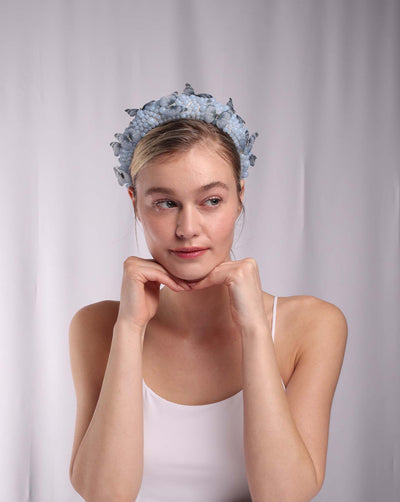 Model is wearing a high headband decorated with different sized matt beads as well as organza butterflies.