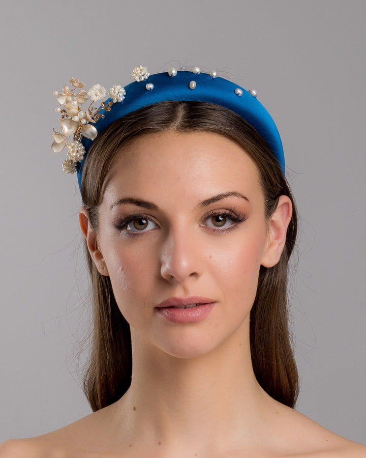 Model is showcasing the front close up of teal silk sateen headband, a favourite yet hard to find colour decorated with mother of pearl wired flowers as well as mother pearl balls and beads. The pearl on the headband elevates the idea of a simple headband to a whole new level. Made by Merve Bayindir Millinery.